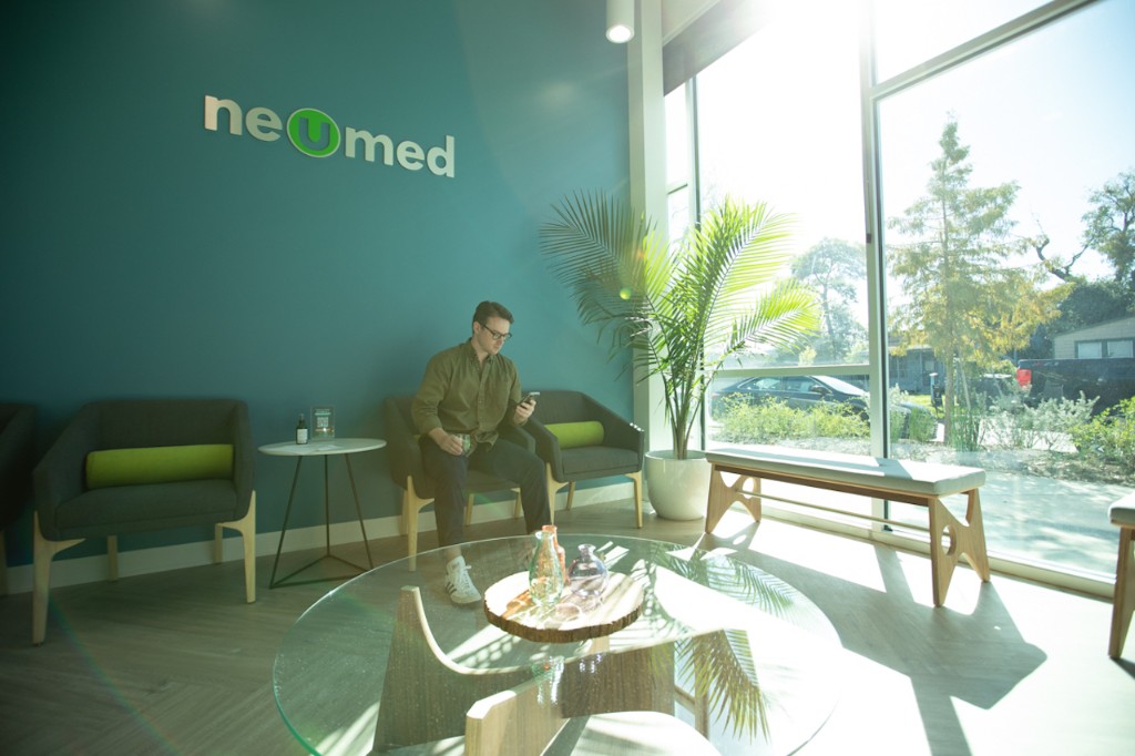 Patient seated in a bright NeuMed waiting lounge with natural light